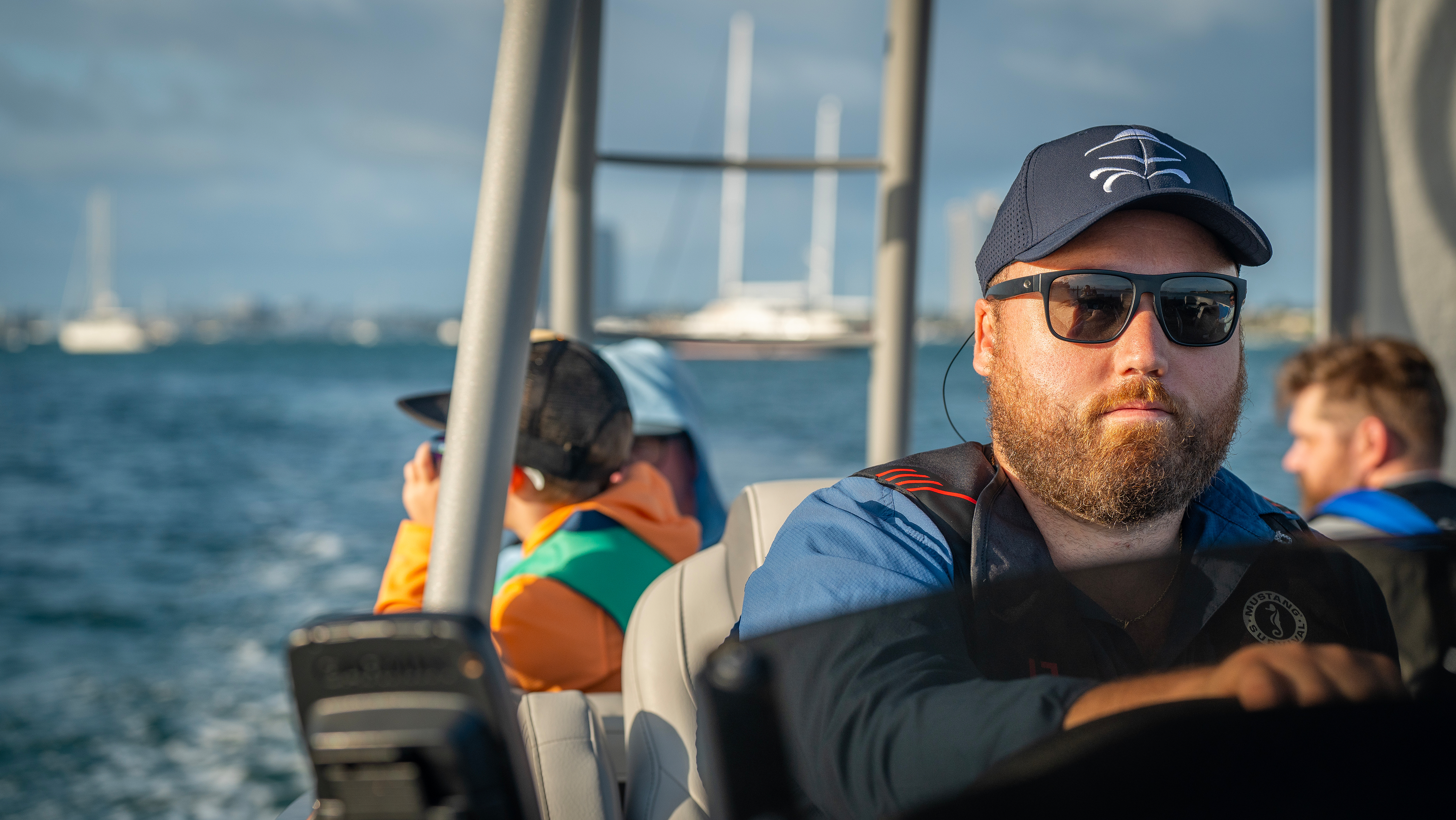 A man drives a boat with kids in the background, drowning prevention concept. 