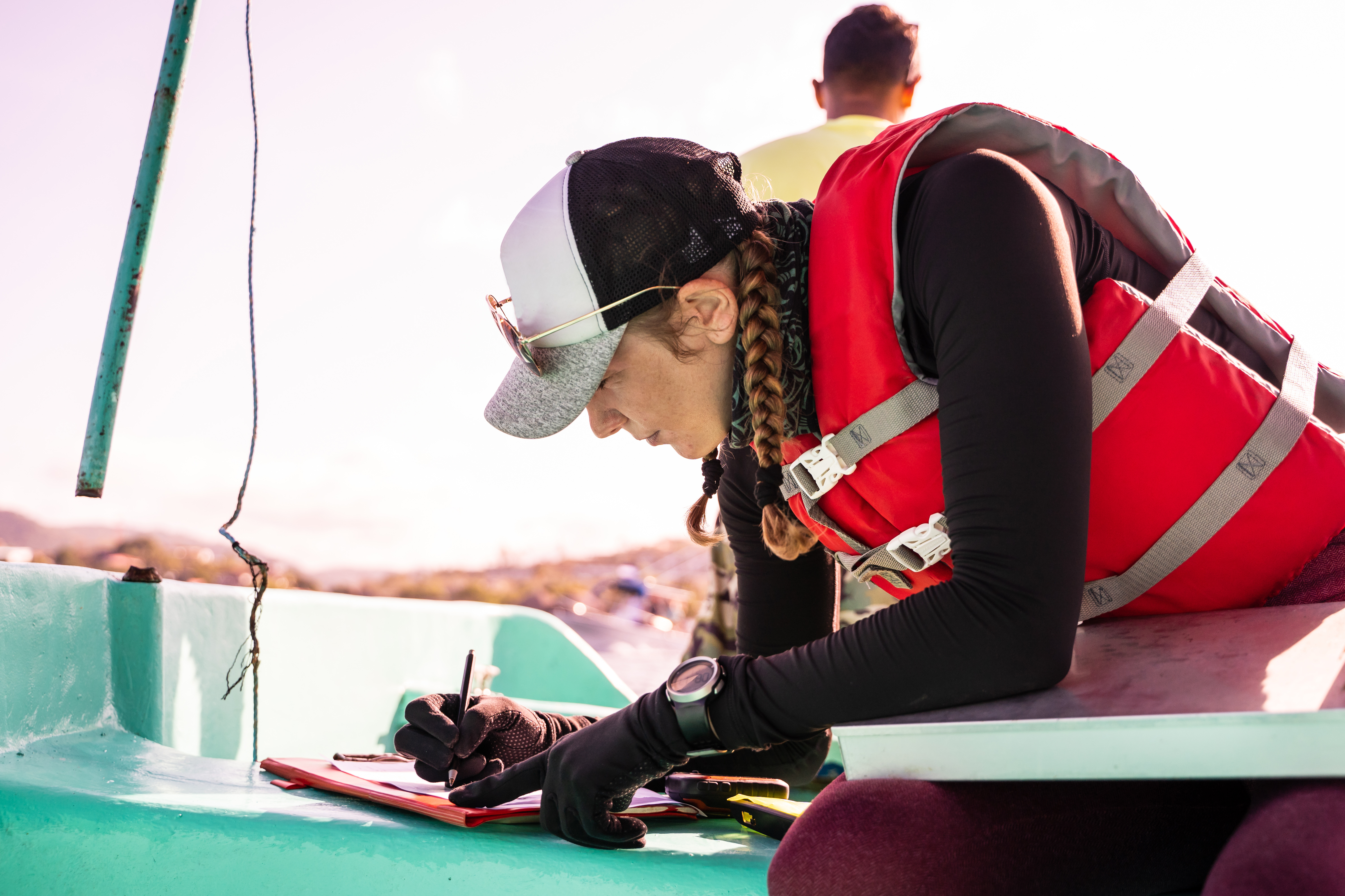 A woman making notes on a clipboard on a boat, fire extinguishers for boats. 