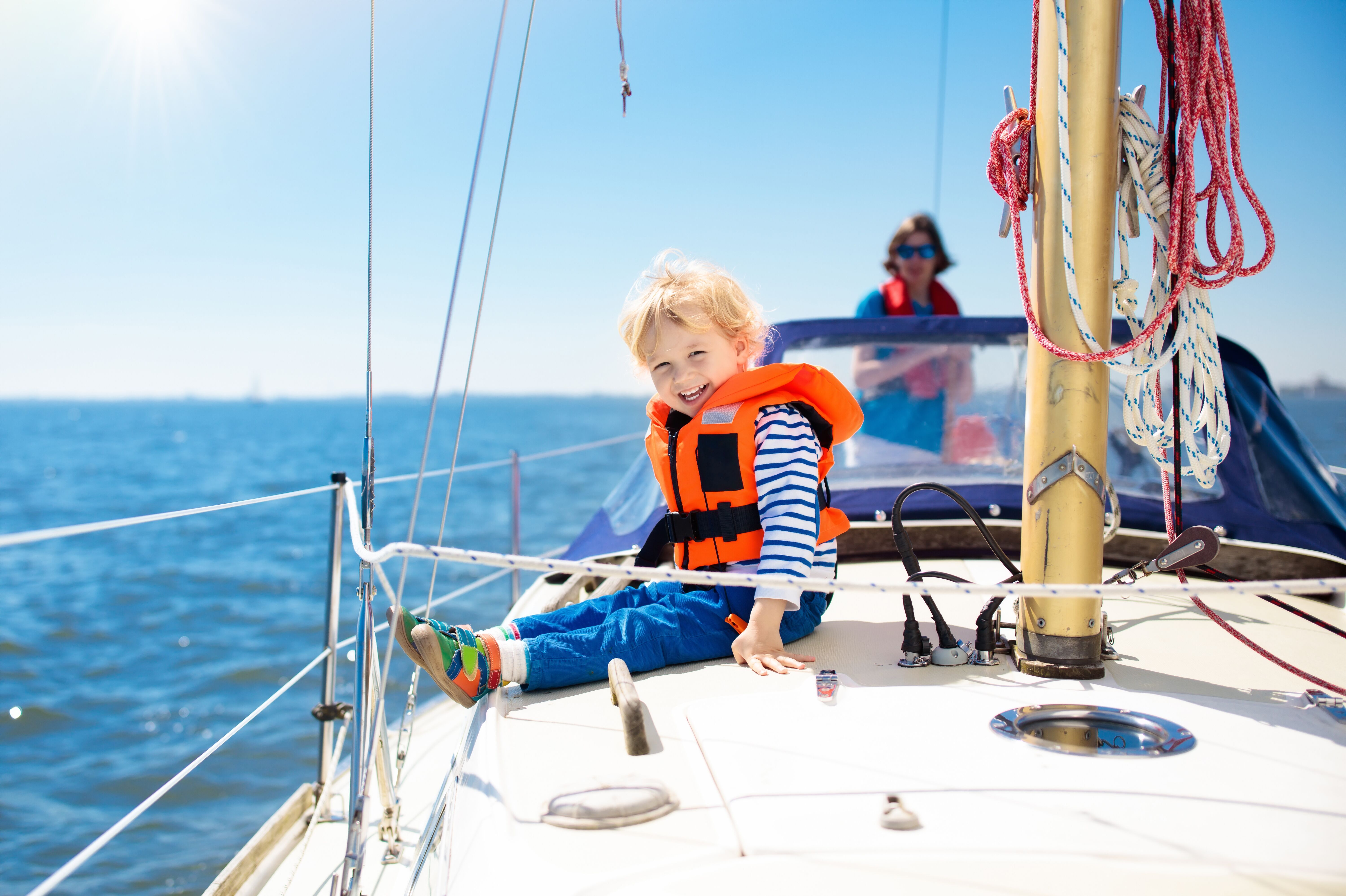 A smiling child wearing a lifejacket on a sailboat. 
