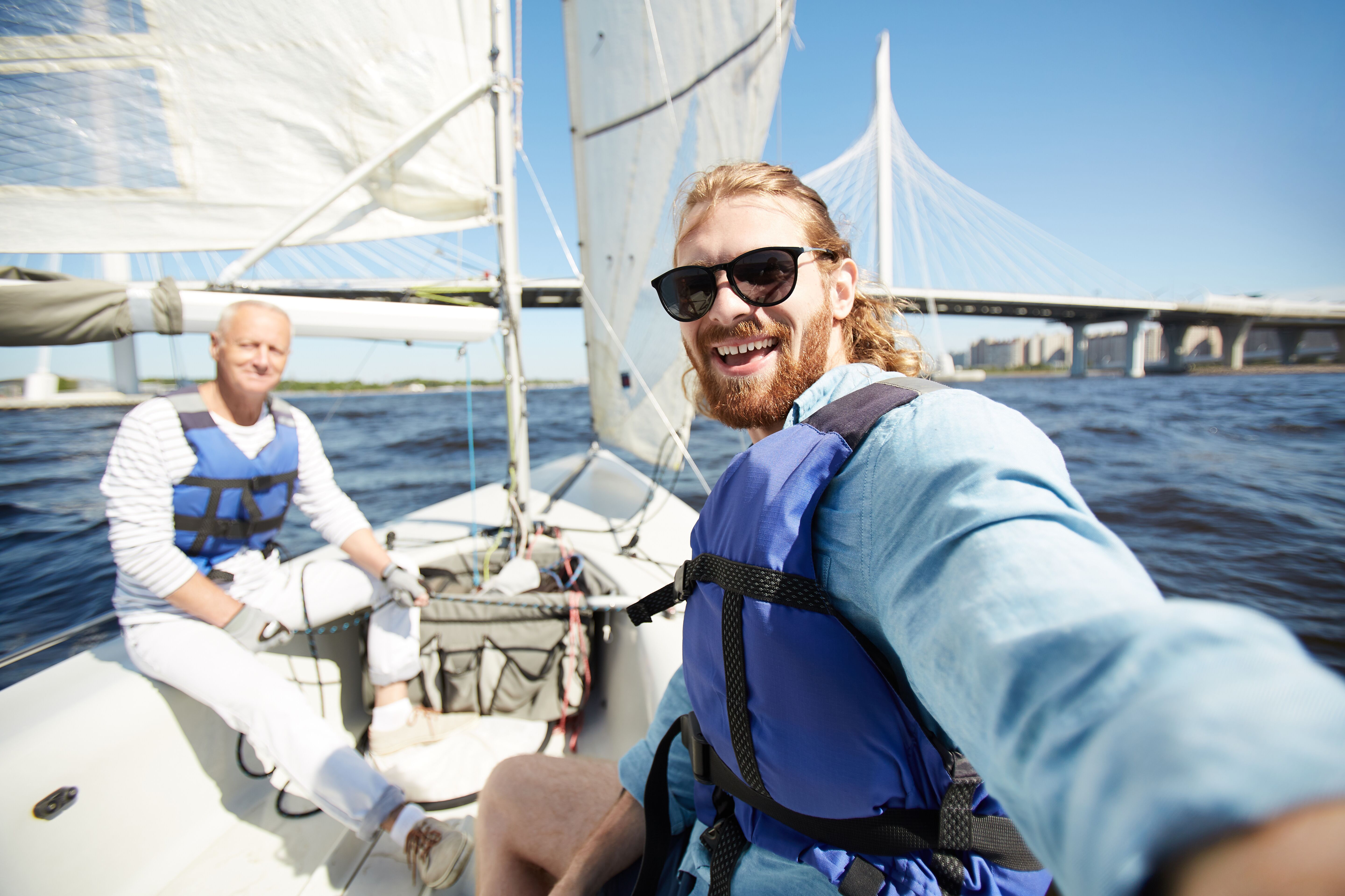 Two smiling men enjoying a sailboat. 