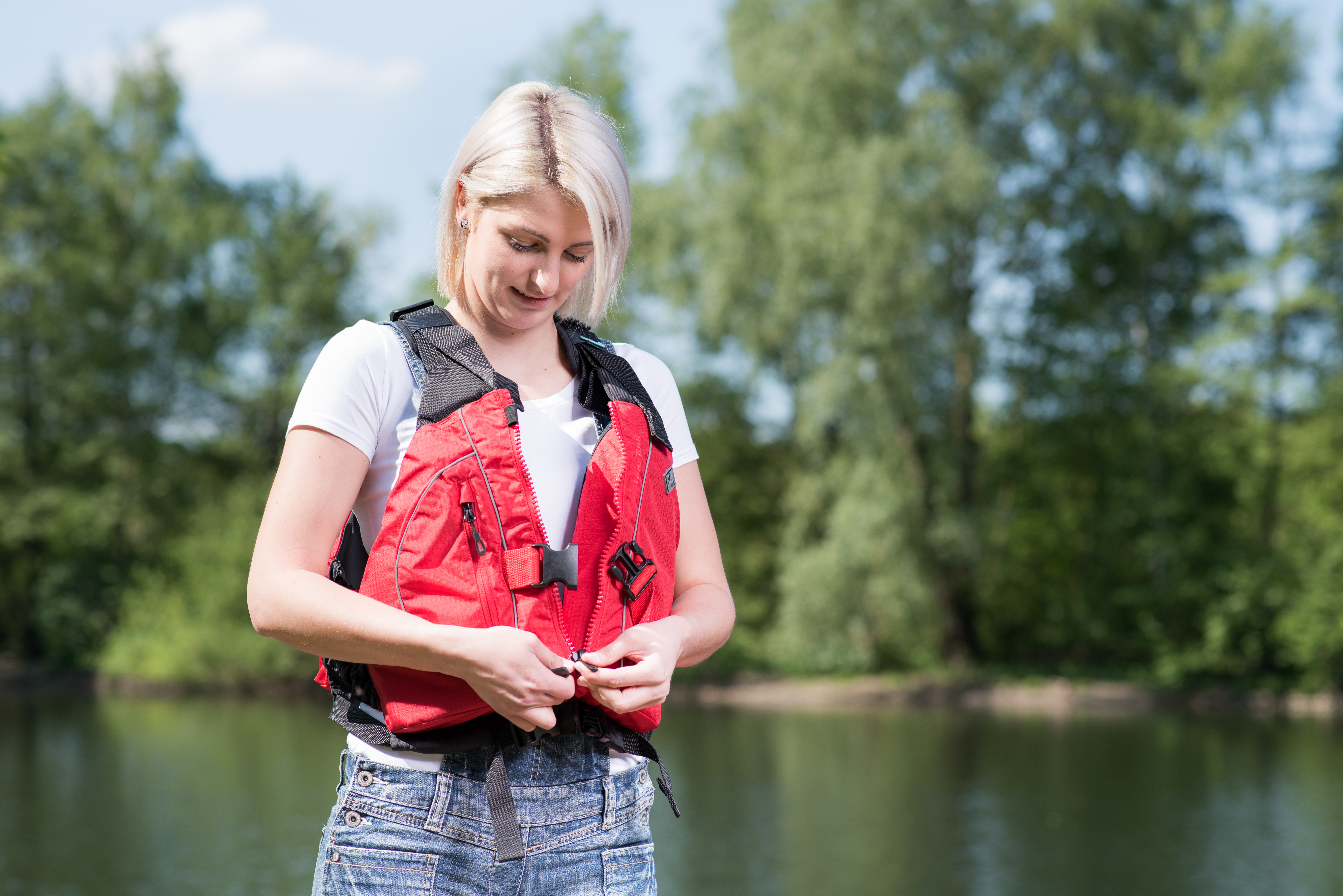 A woman wears and fastens a lifejacket, canoe lifejacket concept. 