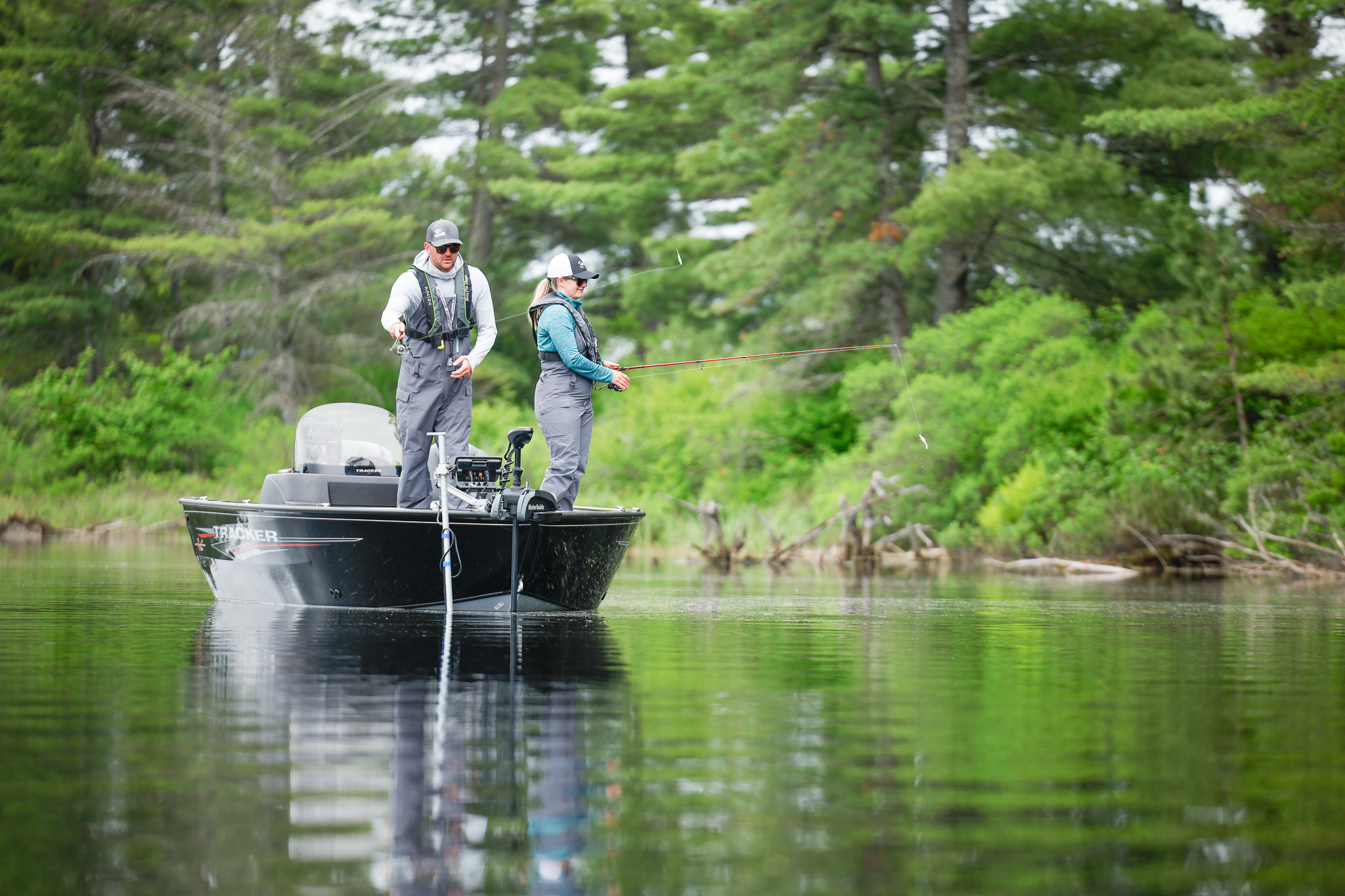 Two people wearing lifejackets standing on a fishing boat with lines in the water, catch alligator gar concept. 