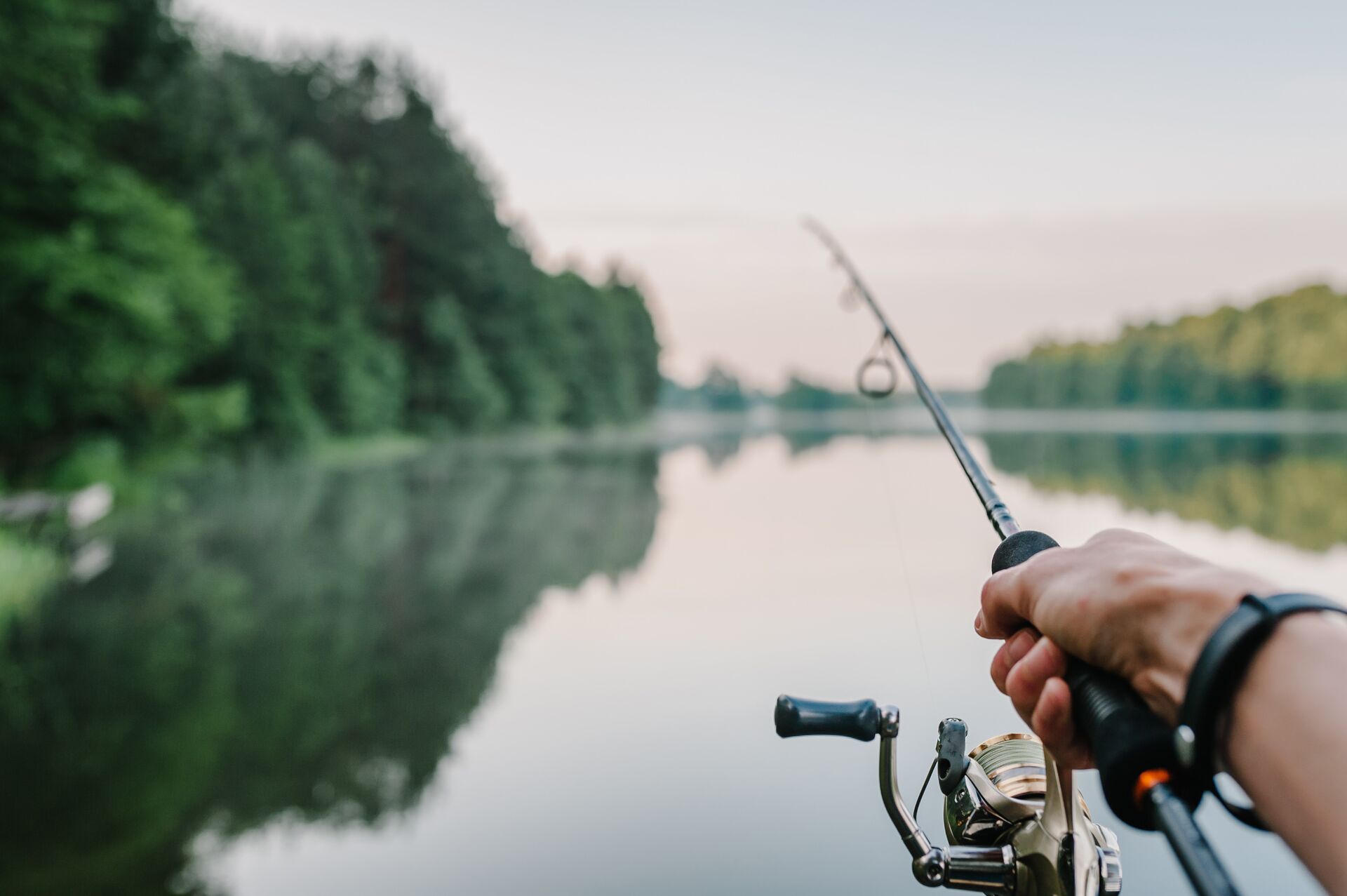 A hand holding a fishing rod over water, how to catch alligator gar concept. 