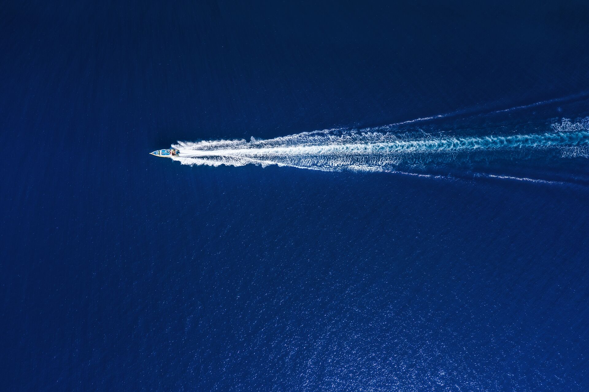 Aerial view of a boat creating a wake on the water, wake surfing behind a boat concept. 