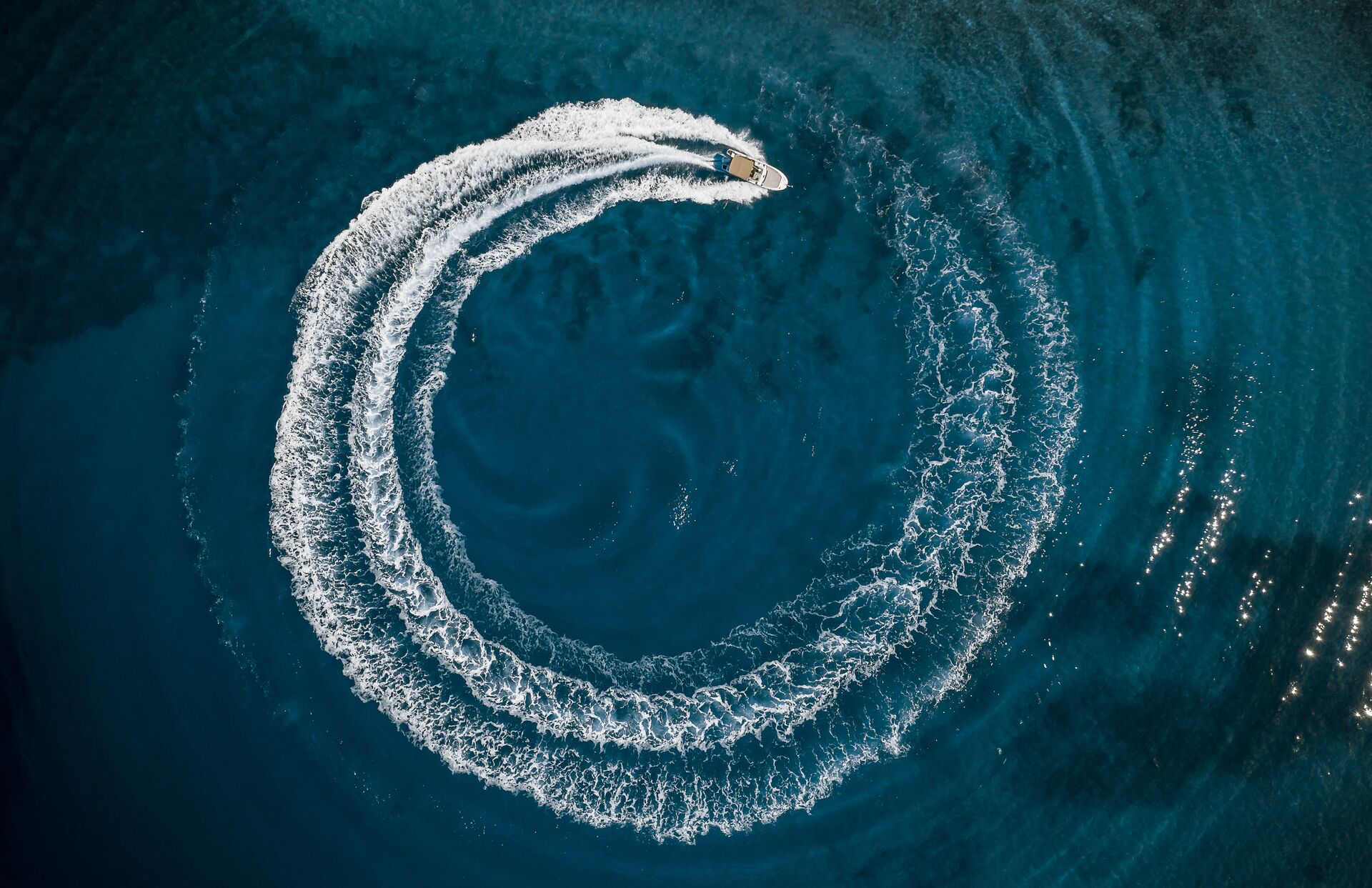 Aerial view of a boat driving in a circle creating a wake, stay safe when wake surfing behind boats concept. 