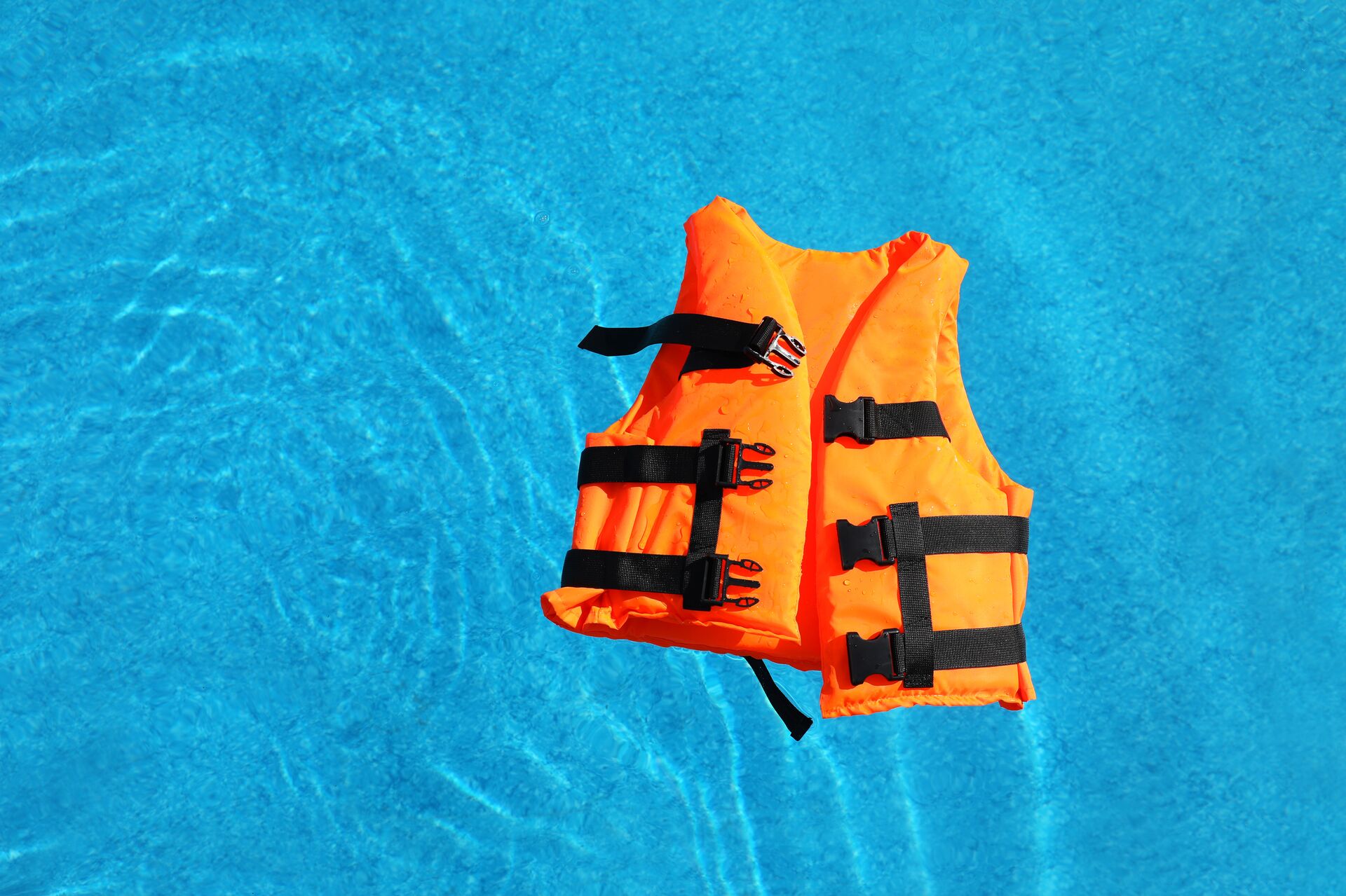 An orange lifejacket floats on water, stay safe when wake surfing concept. 