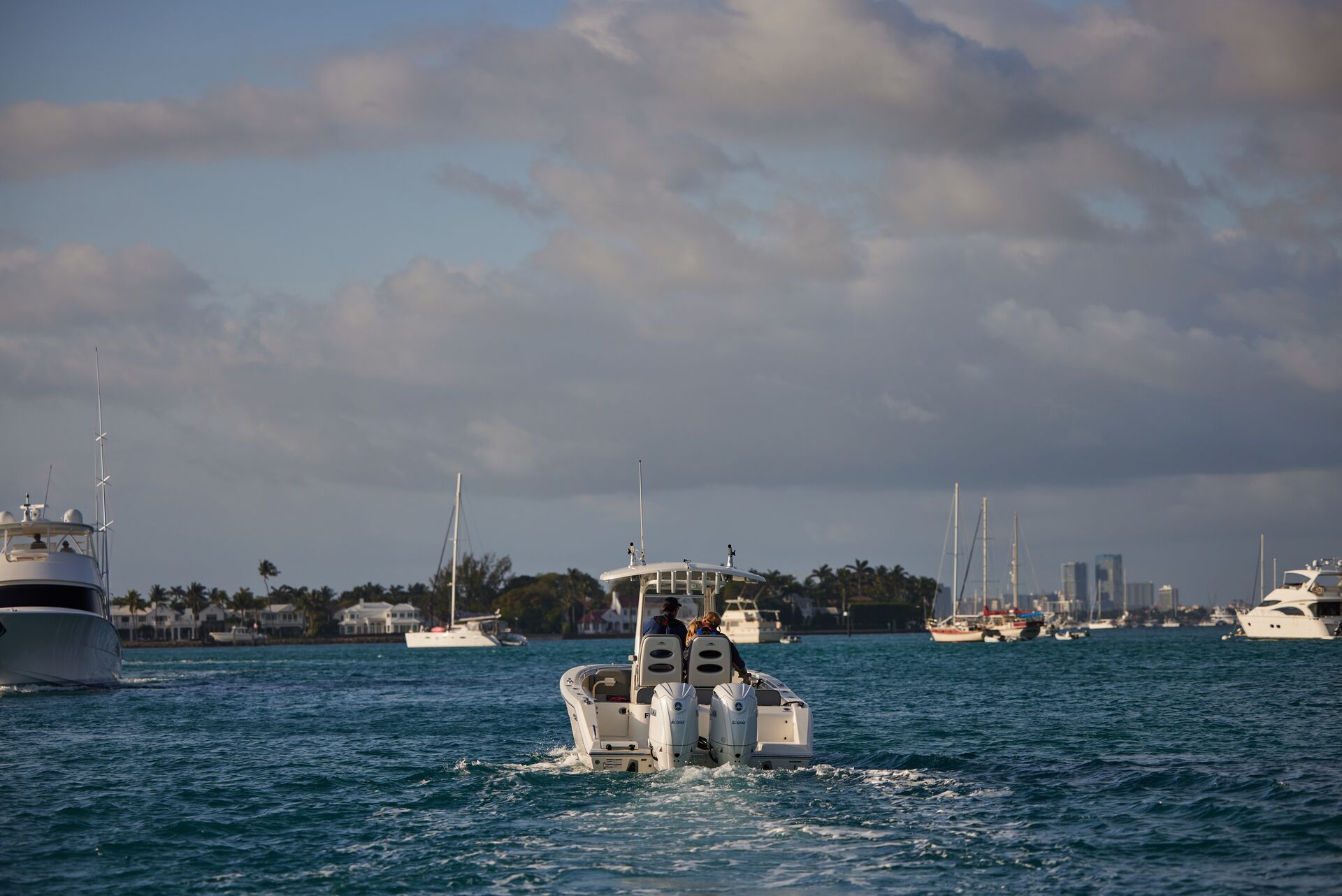 The back of a boat on the water showing a gas motor, electronic boat motor vs gas concept. 