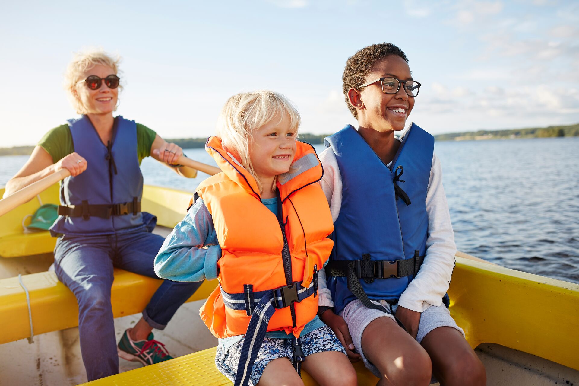 A woman and two children wearing lifejackets on a boat, Ontario boat license concept. 