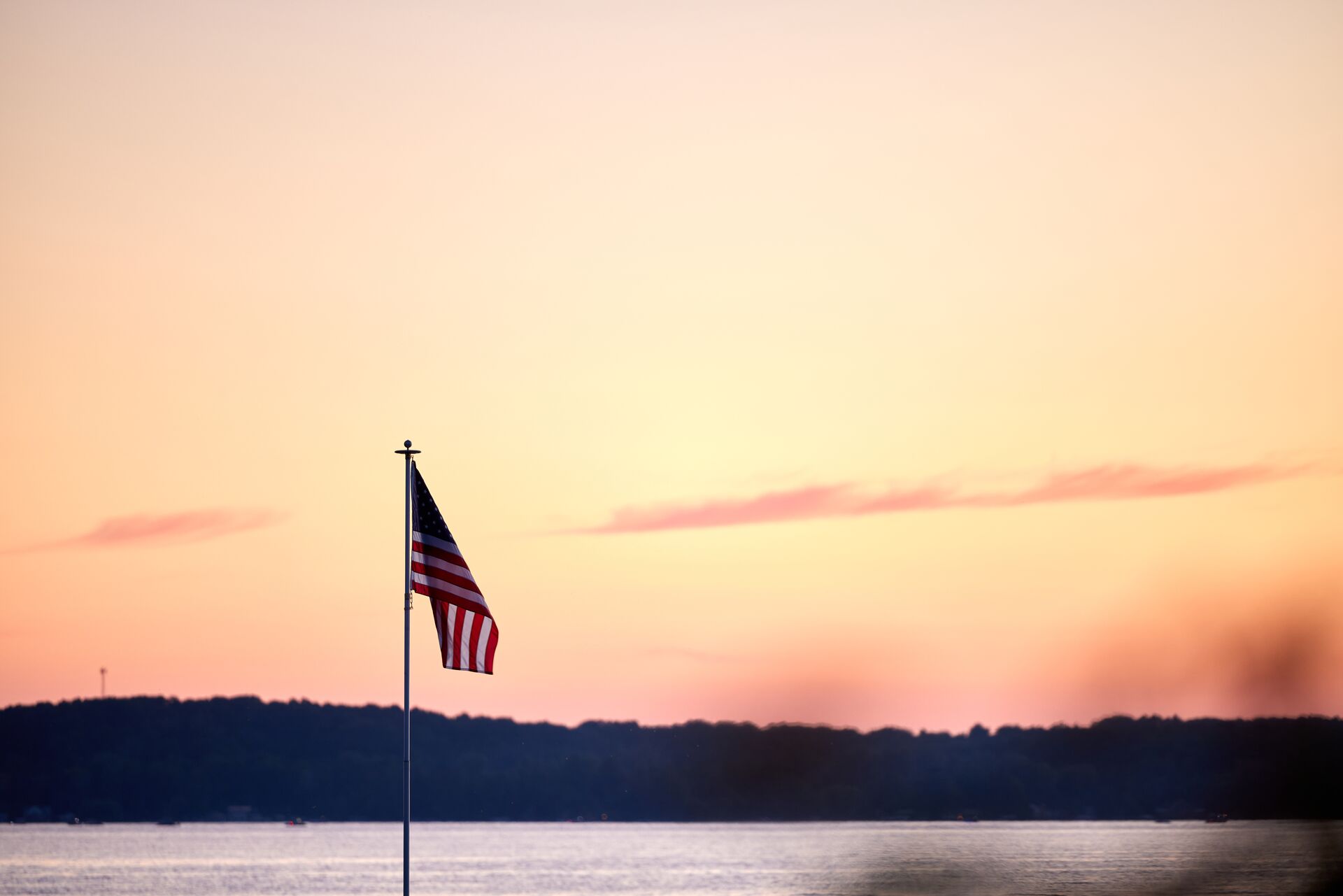 The U.S. flag over a lake a dusk, red and white flags concept. 