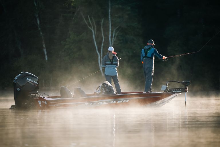 Two people fishing on a bass boat. 