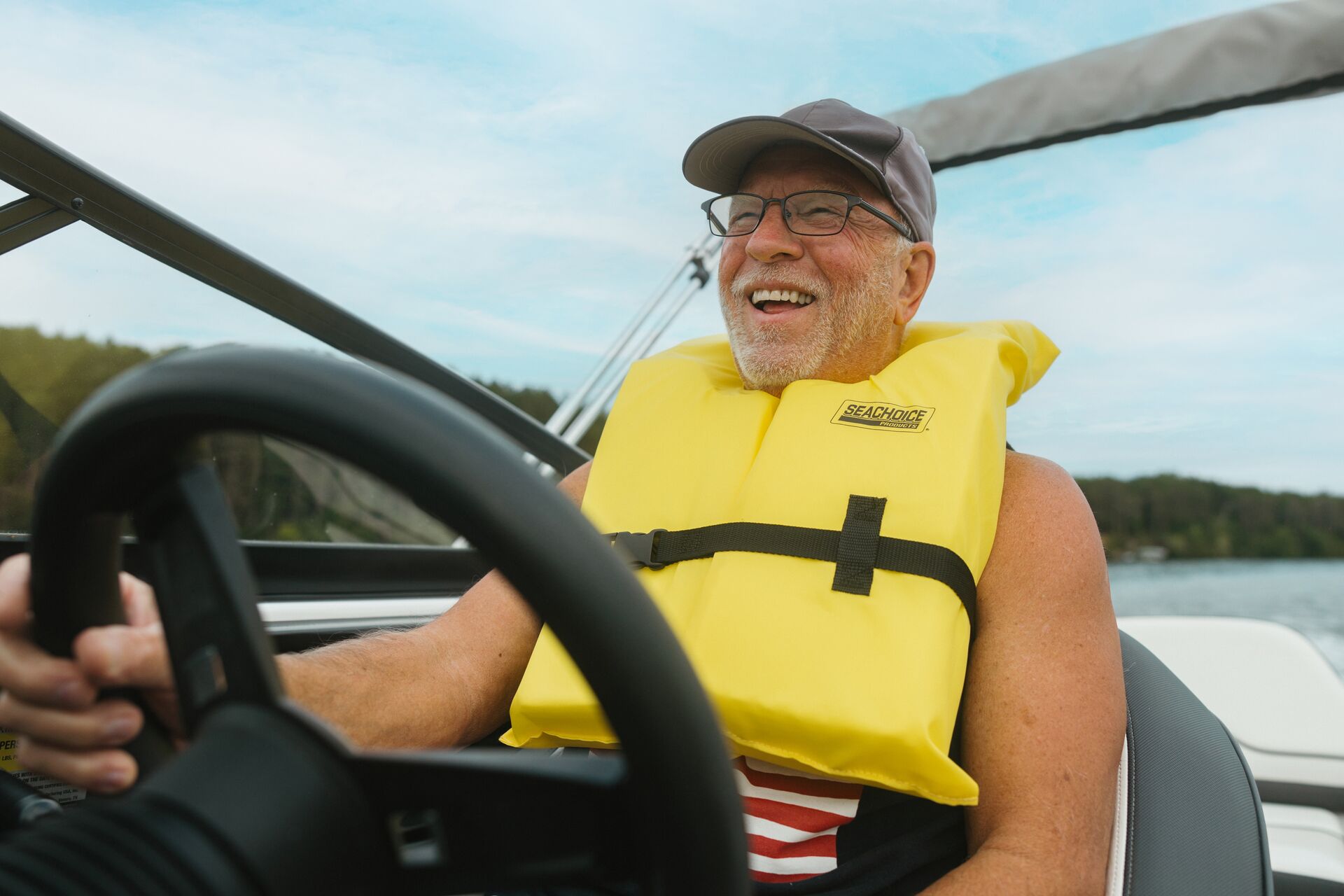 A smiling man drives a boat, getting your Alberta boating license concept. 