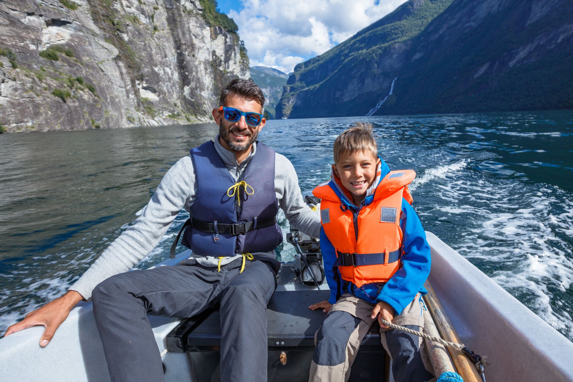 A man and boy wearing warm clothes and life jackets on a small boat, watch for hypothermia symptoms concept. 