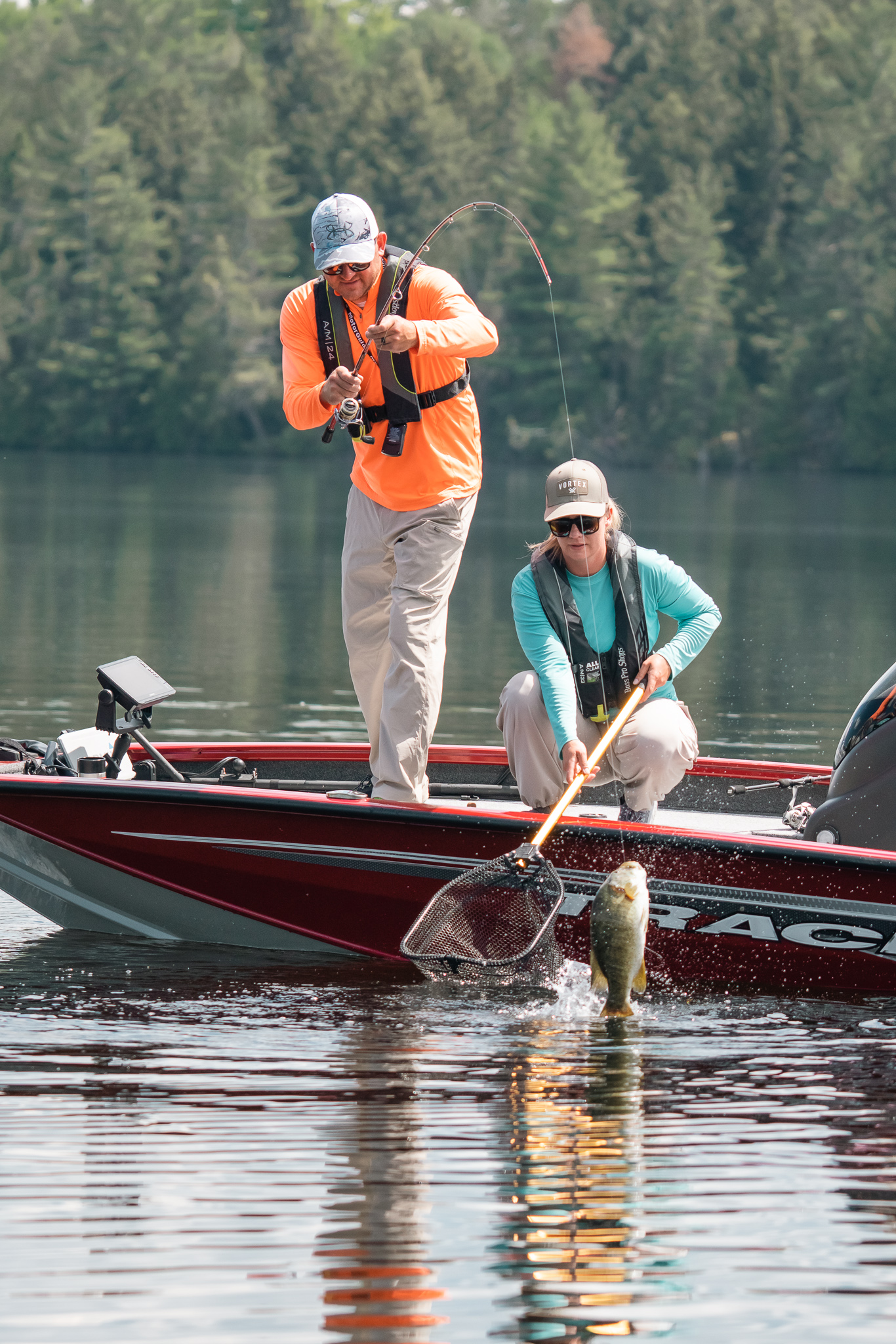 Two people in a boat reeling in a fish. 