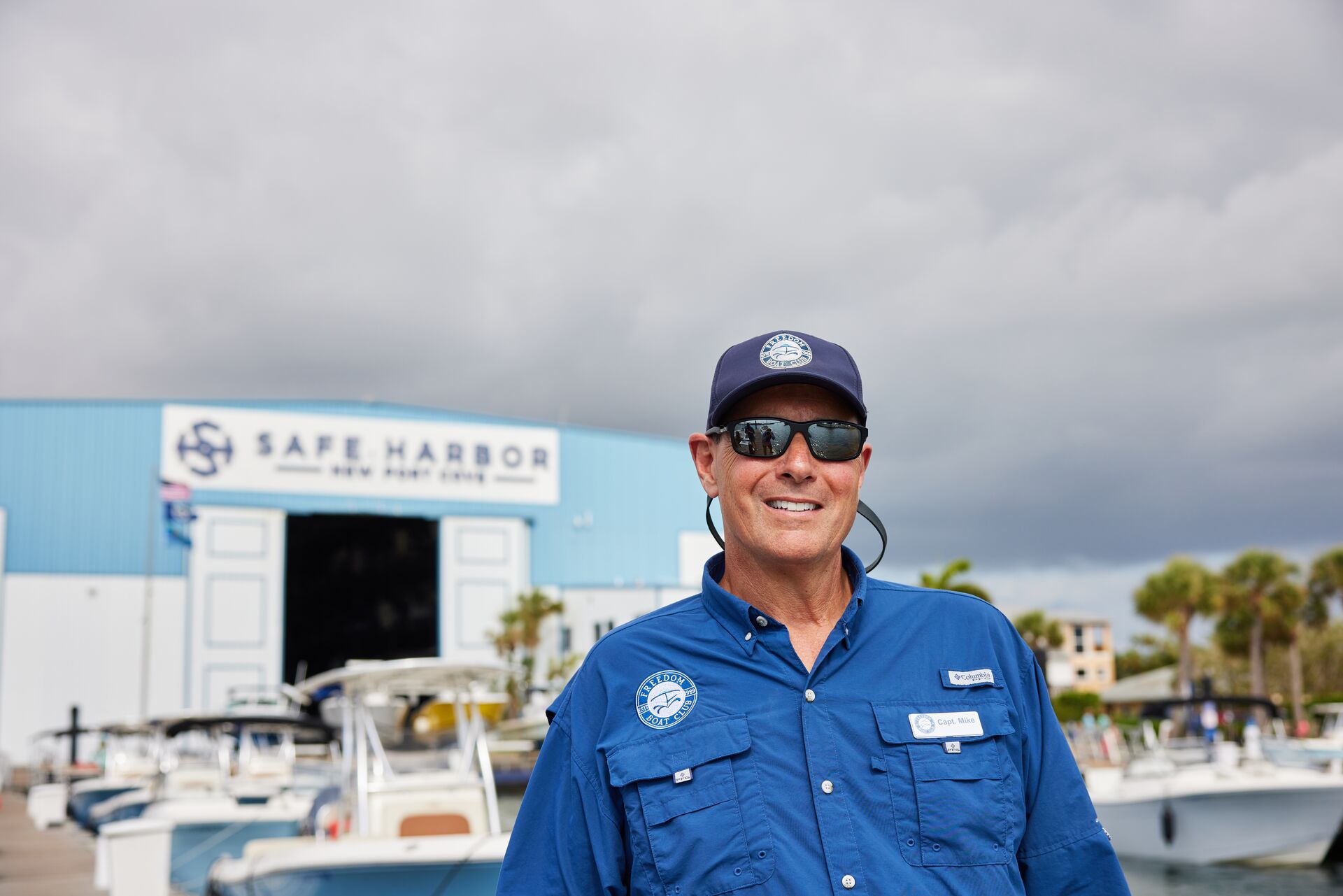 A man smiles standing near boats on a dock, boat captain license canada concept.