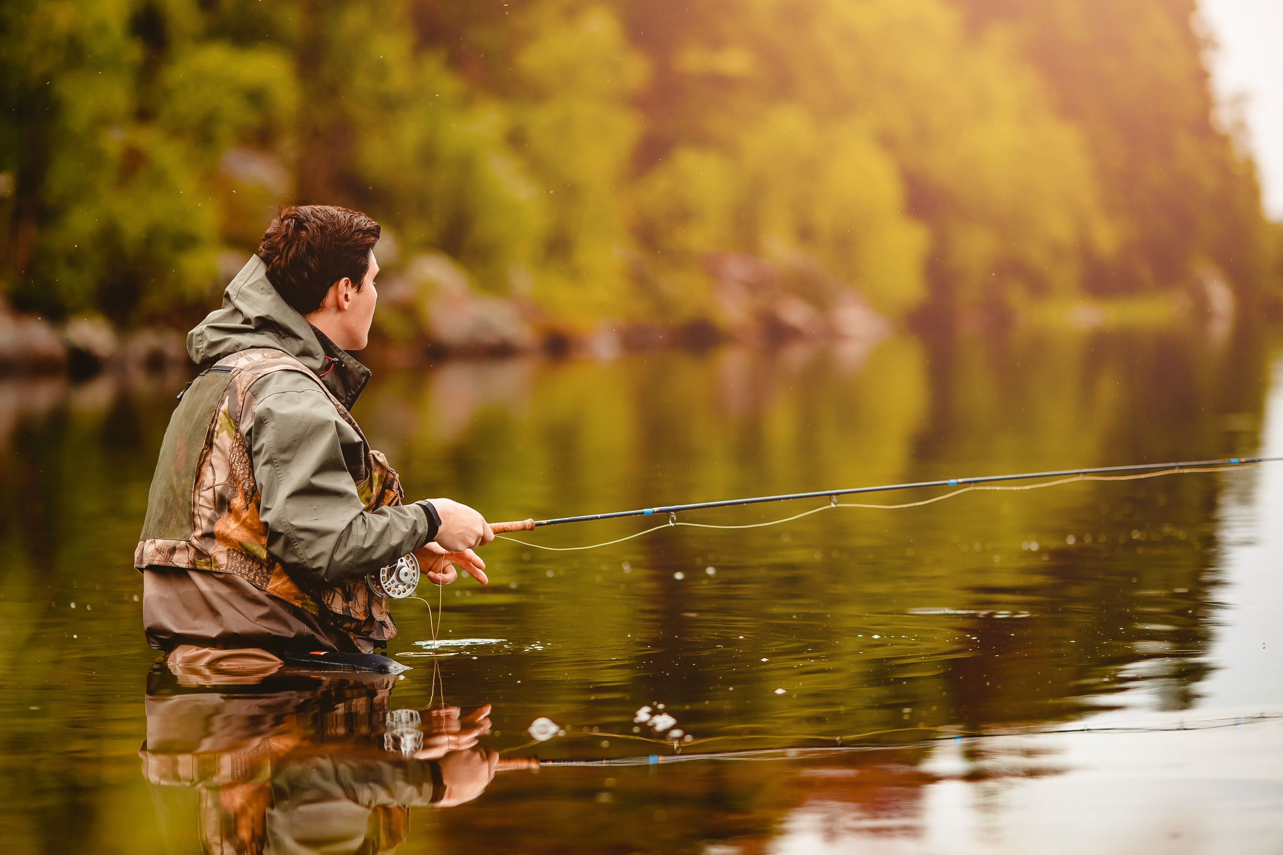 A man in a river while fly fishing.