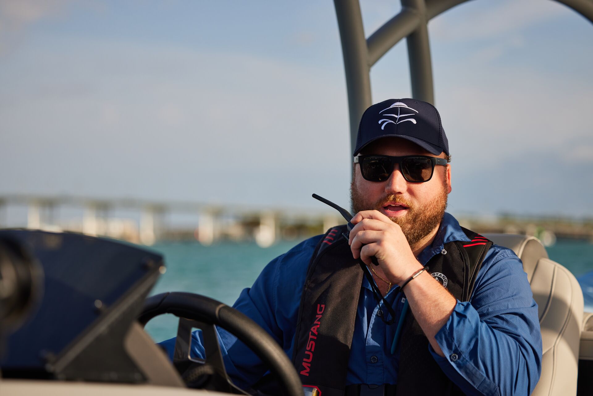 A man drives a boat while using a radio, concept of Coast Guard requirements for boats.