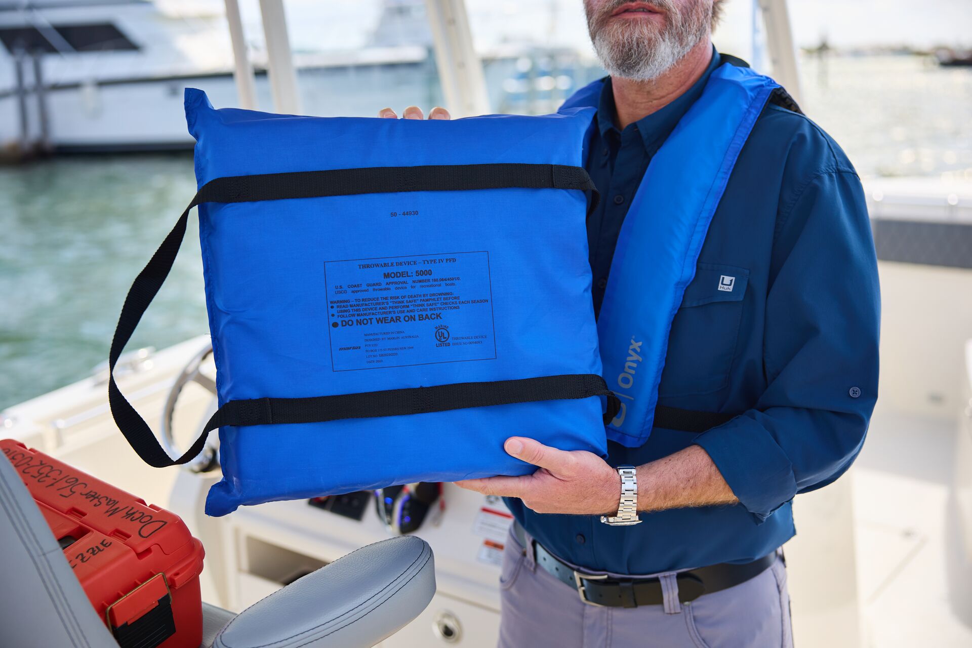 A man holds a throwable flotation device while on a boat. 