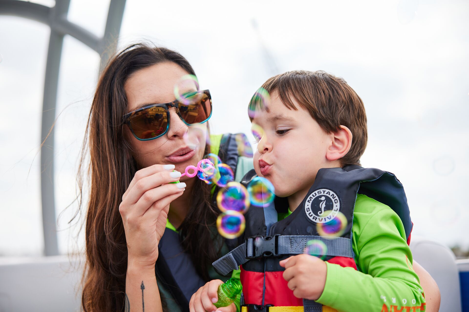 A woman and child blow bubbles while wearing lifejackets on a boat, things needed on a boat concept. 