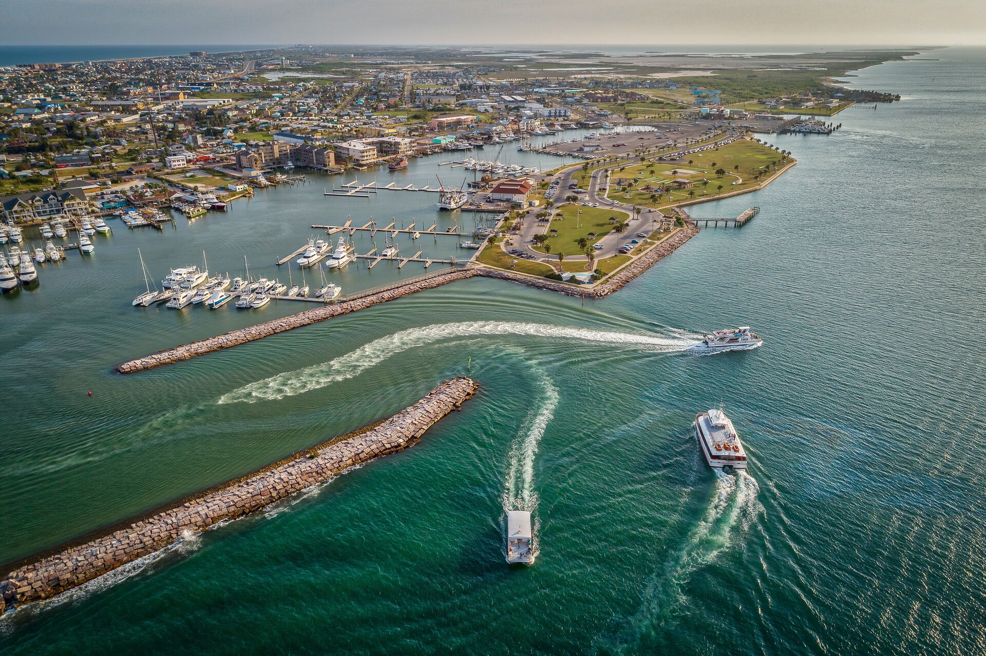 Aerial view of boats coming in and out of a marina on the ocean. 