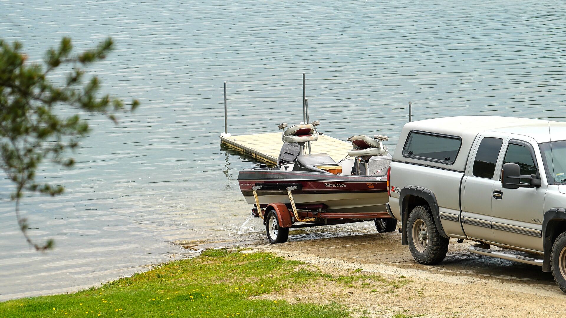 Truck backs a boat on a trailer into the water, how to launch a boat alone concept. 