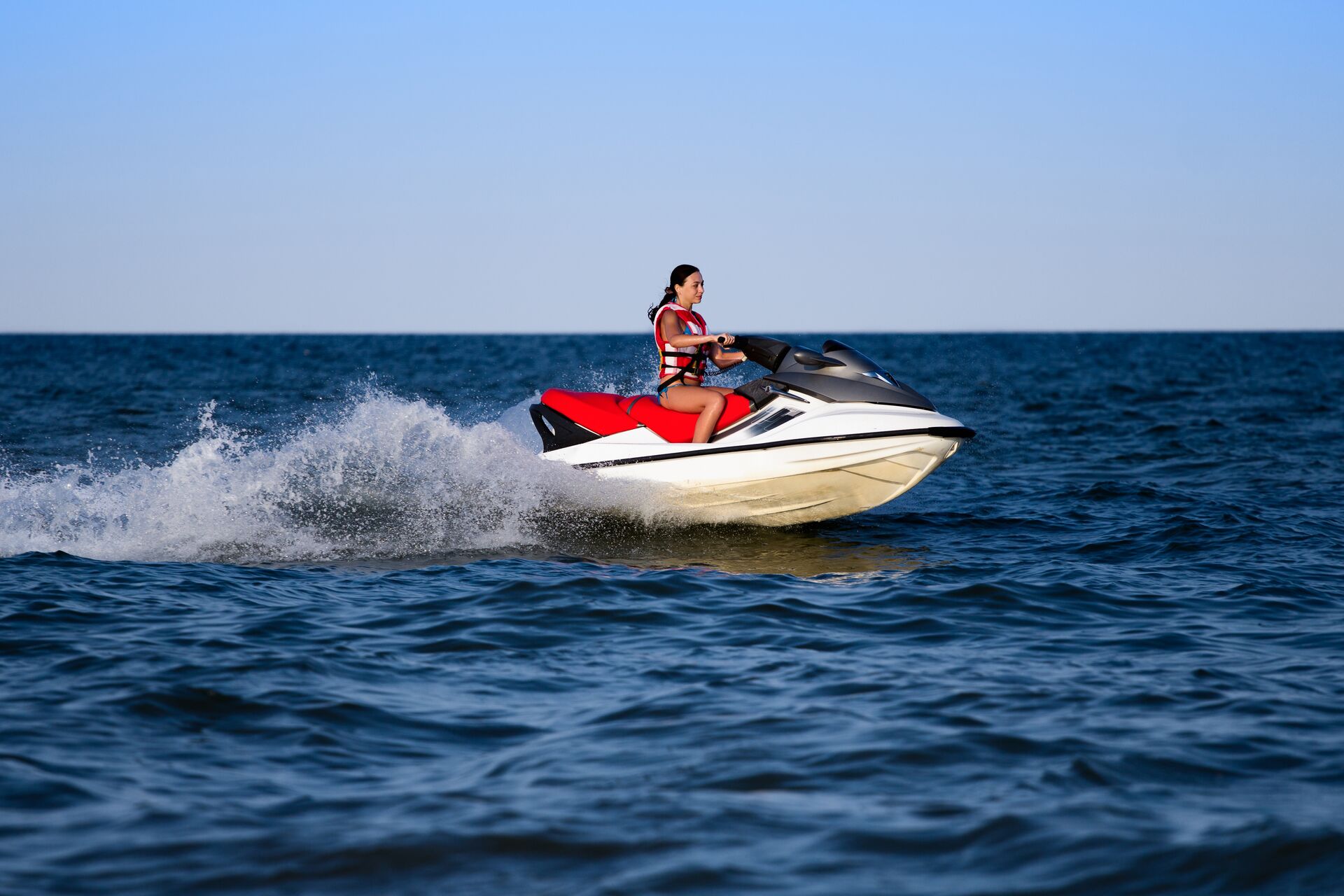 A girl rides a PWC on the water. 