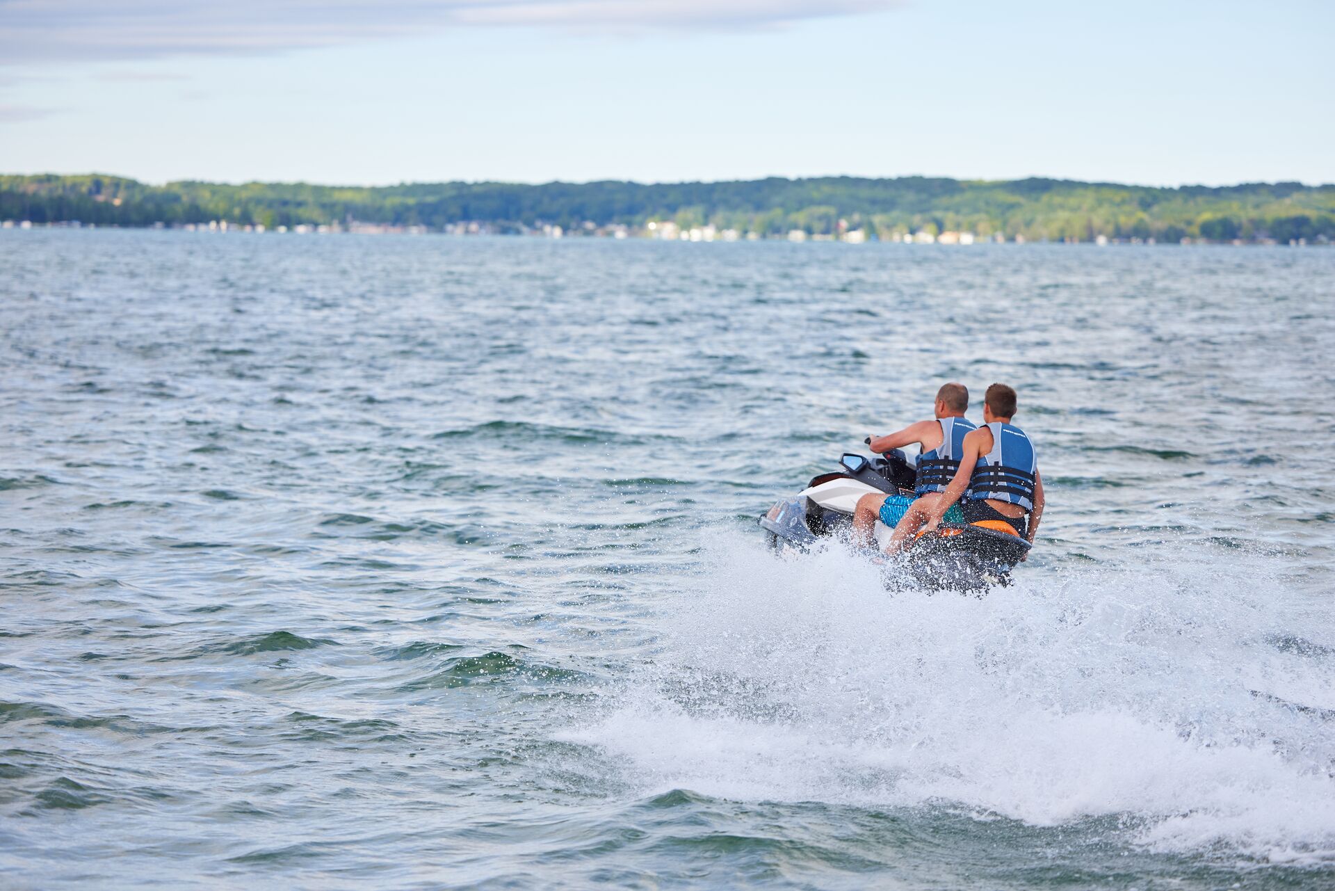 Man and boy turning on a PWC in the water. 