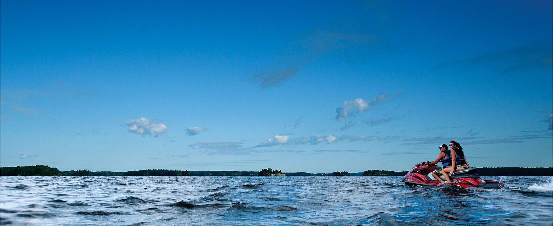 Man and woman ride a jet ski on a lake. 