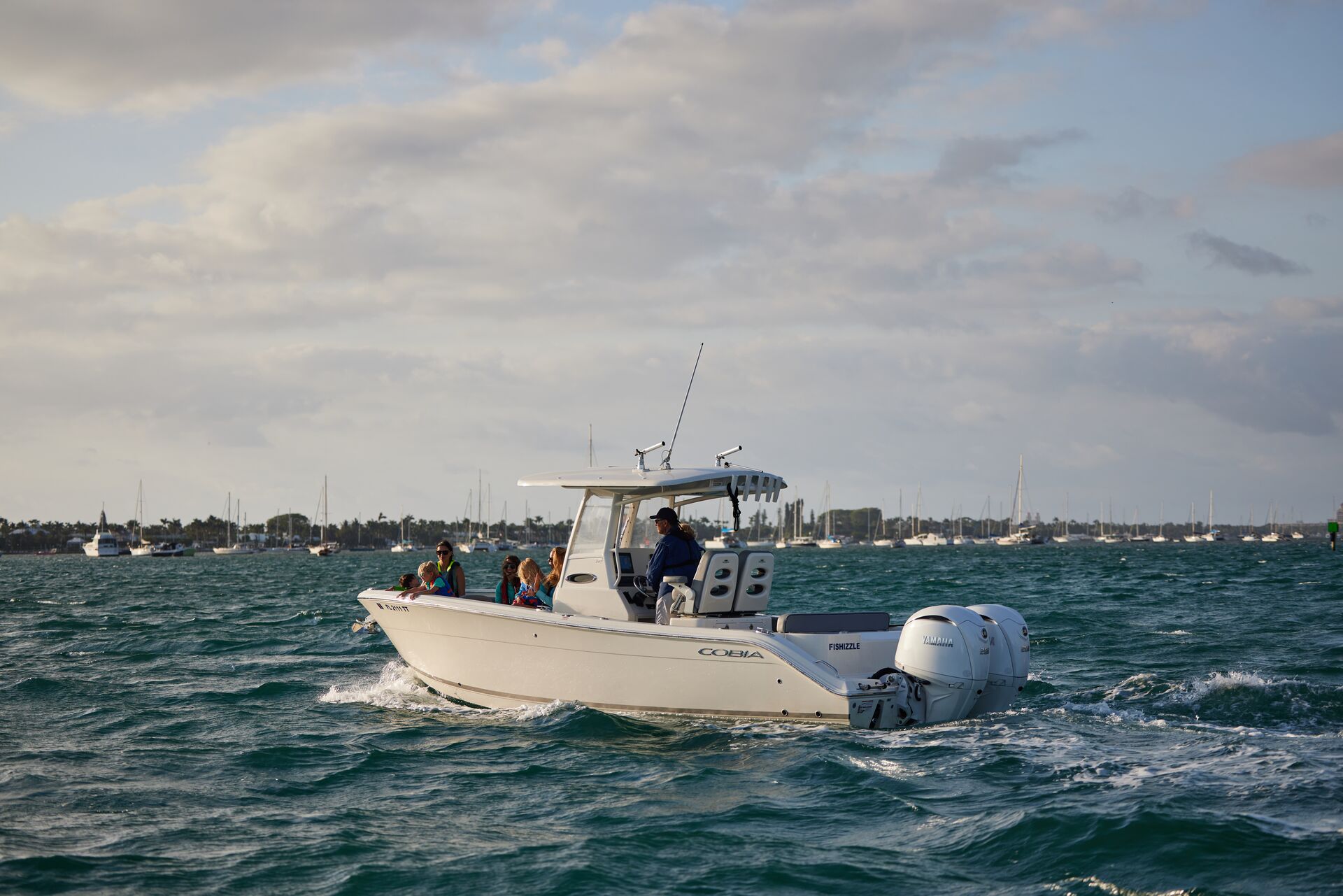 A center console fishing boat on the water with people in life jackets on board. 