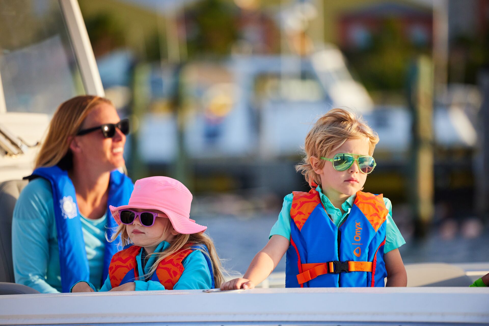 Kids and woman in life jackets on a boat. 